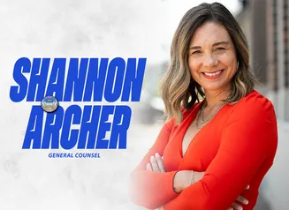 Shannon Archer in front of a gray background with her name in bold blue font